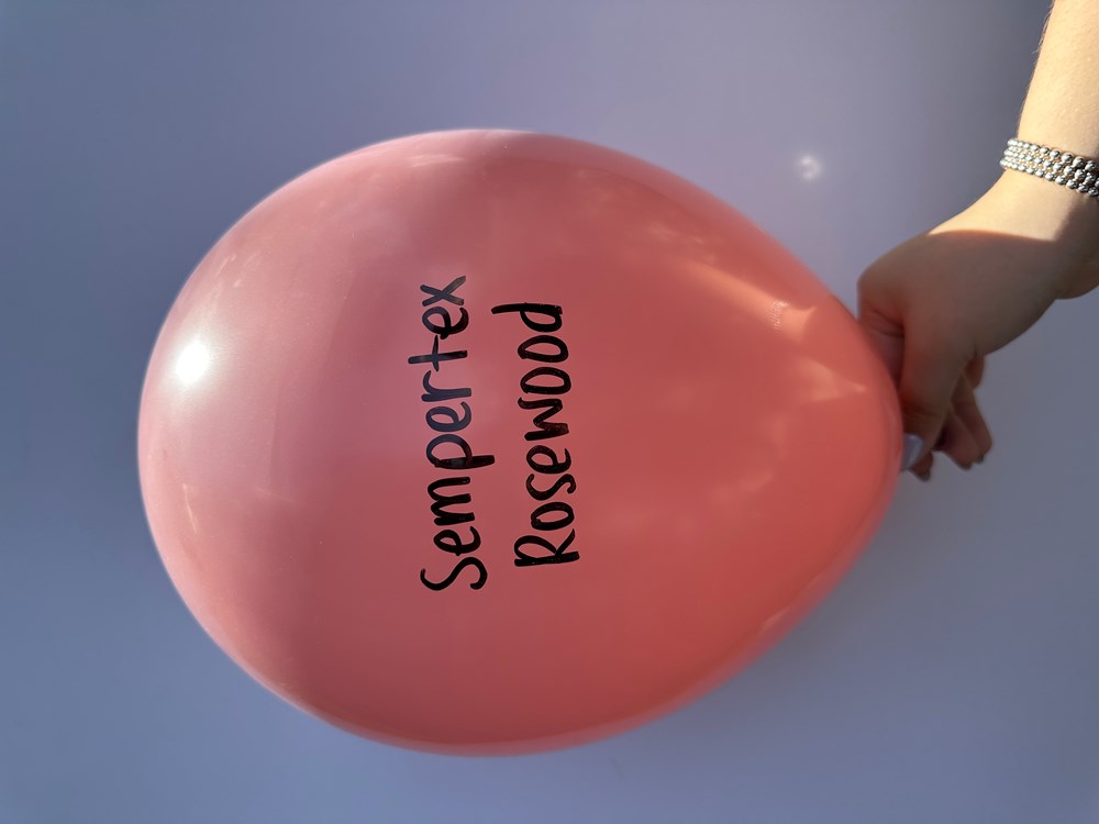 36-inch rosewood-colored latex balloon with black Sempertex Rosewood print held by hand.
