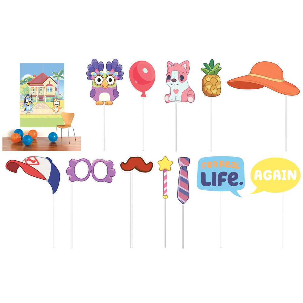 Colorful Bluey-themed party photo props including house backdrop, dog characters, balloon, pineapple, hat, glasses,.