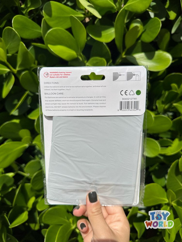 Folded white star-shaped foil balloon in flat packaging with hanging tab, held by hand against green leaves background.