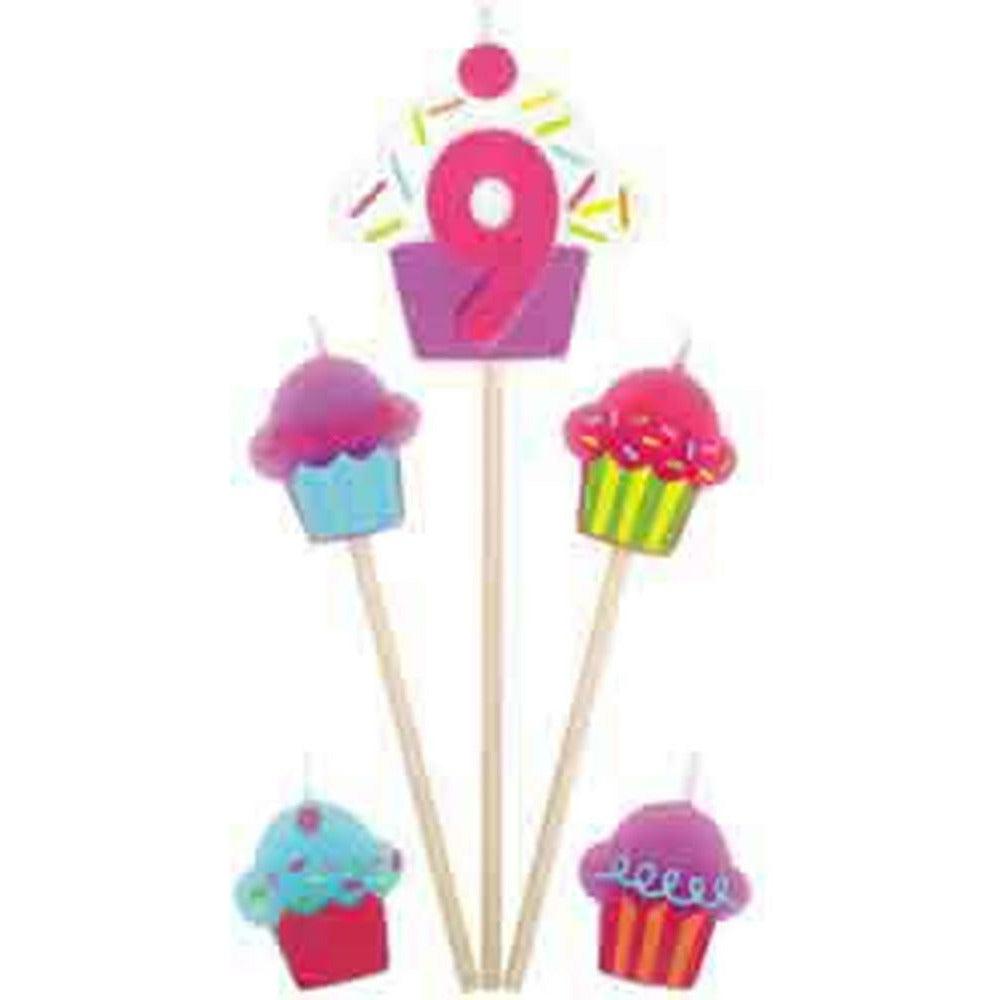 Cupcake shaped candles in blue, pink, and purple with a pink number 9 candle on a stick with sprinkles and a cherry on top.