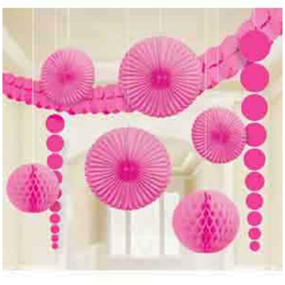 Bright pink paper honeycomb balls and fan decorations hanging in a festive arrangement.