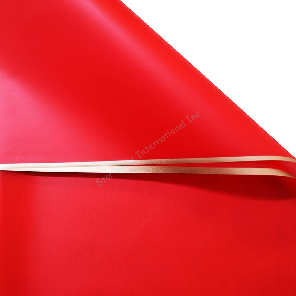 Red wrapping paper with smooth texture and shiny gold edges, neatly rolled.
