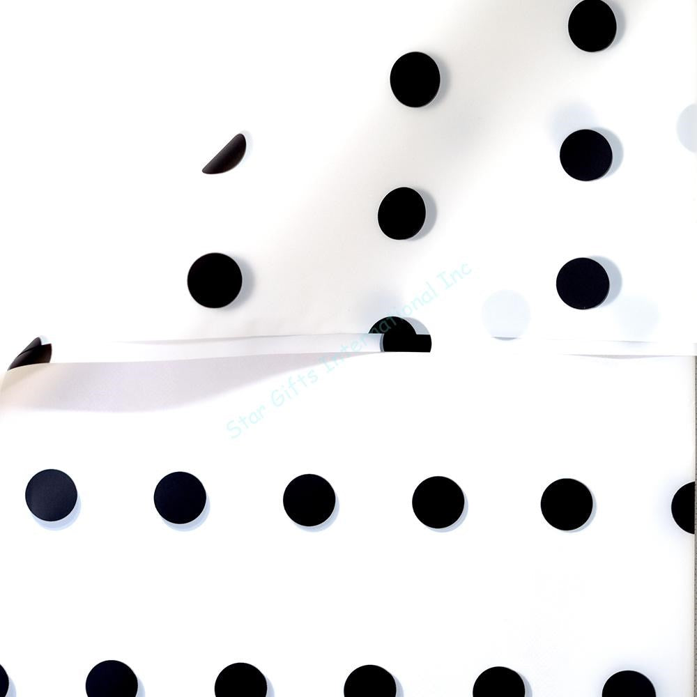 White wrapping paper with large, evenly spaced black polka dots on smooth, glossy paper sheets.