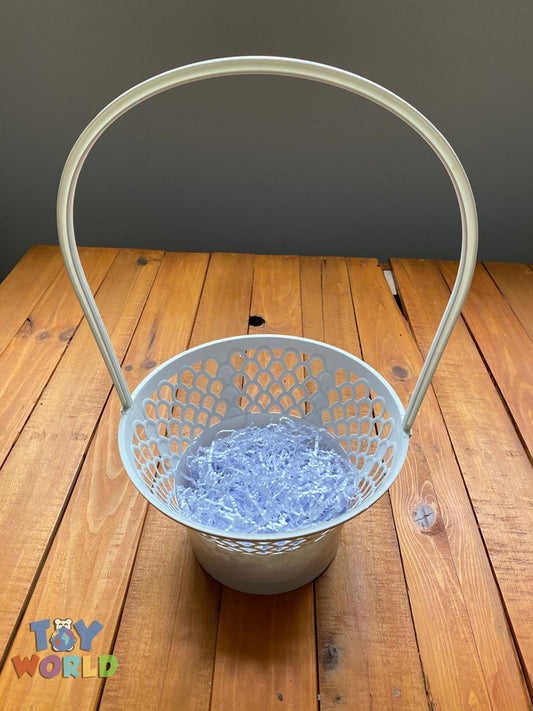 White plastic basket with perforated sides, round base, and tall curved handle, filled with blue shredded paper.