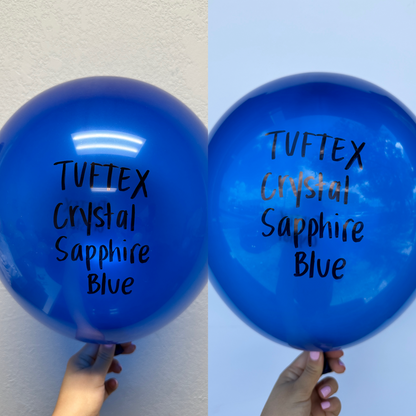 Two shiny 5-inch sapphire blue latex balloons with "Tuftex Crystal Sapphire Blue" printed in black and gold text.