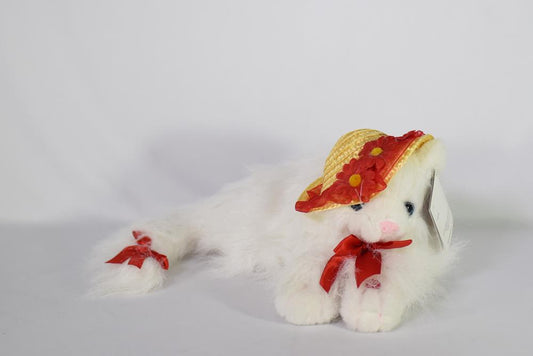 White plush cat wearing a straw hat with red trim and red bow around neck.