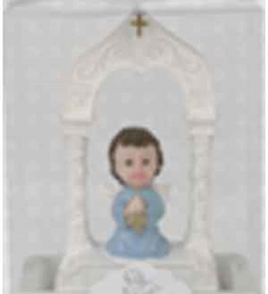 Small angel figurine with dark hair in blue robe holding hands in prayer, set inside a white arch with a gold cross at the.