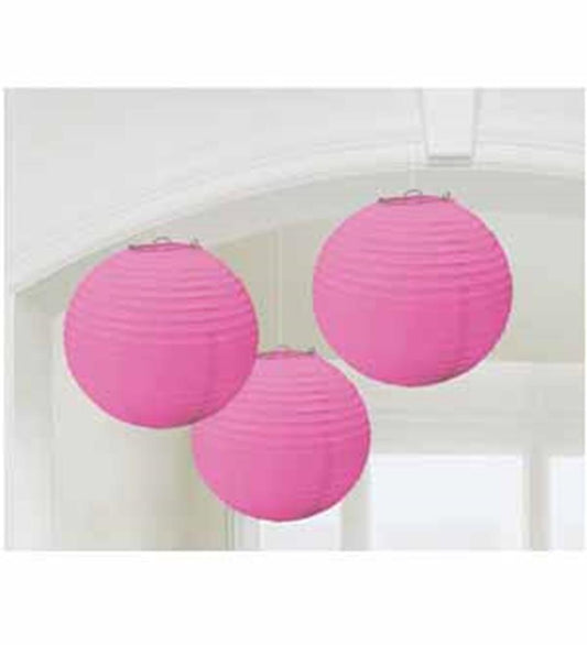 Set of three pink 9-inch round paper lanterns hanging indoors.