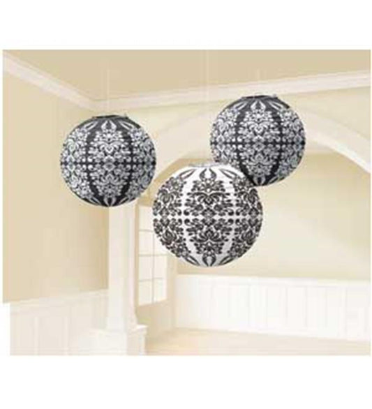 Three black and white paper lanterns with intricate damask patterns hanging indoors.