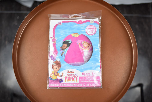Inflatable Fancy Nancy beach ball with pink and purple panels featuring cartoon characters in sealed packaging.