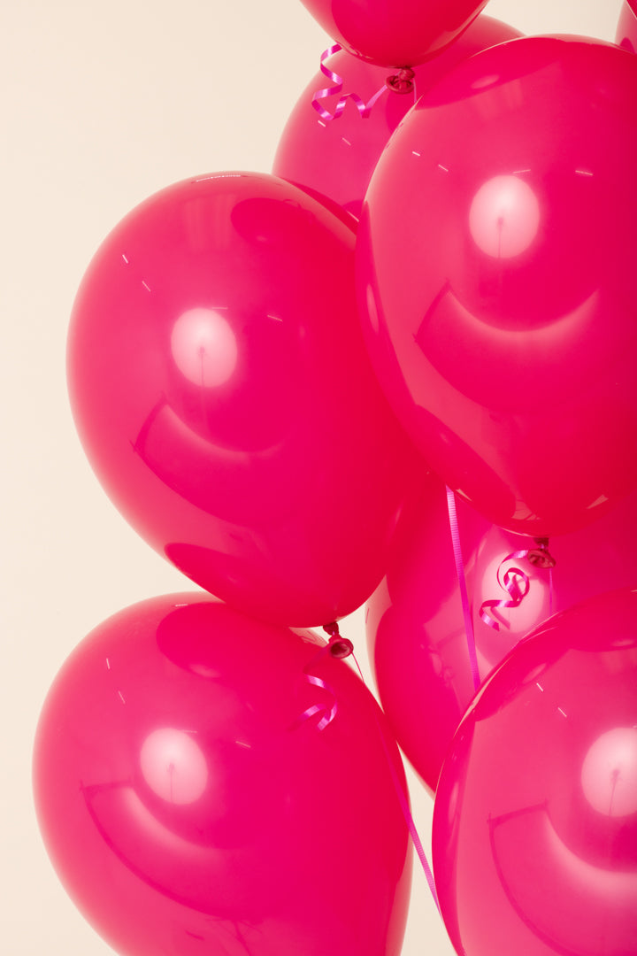 Bright pink shiny latex balloons inflated with helium, round 11-inch size.