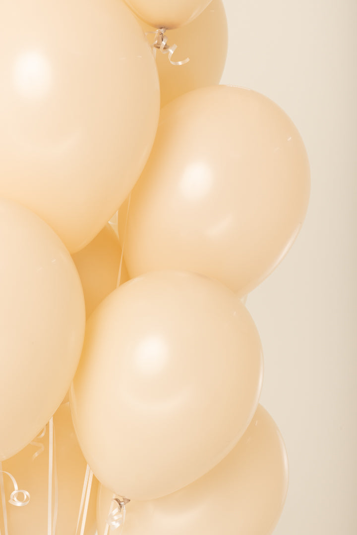 Glossy cream-colored 11-inch latex helium balloon with smooth surface and tied neck.