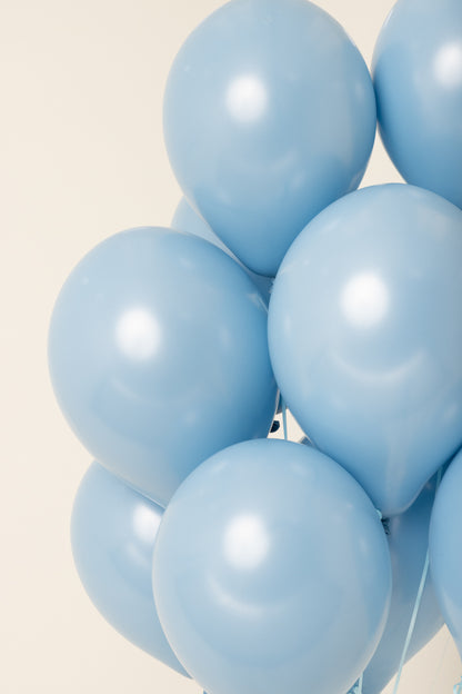 Cluster of shiny, light blue, 11-inch latex helium balloons with round shape.