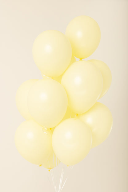 Cluster of pale yellow, round 11-inch latex balloons inflated with helium.