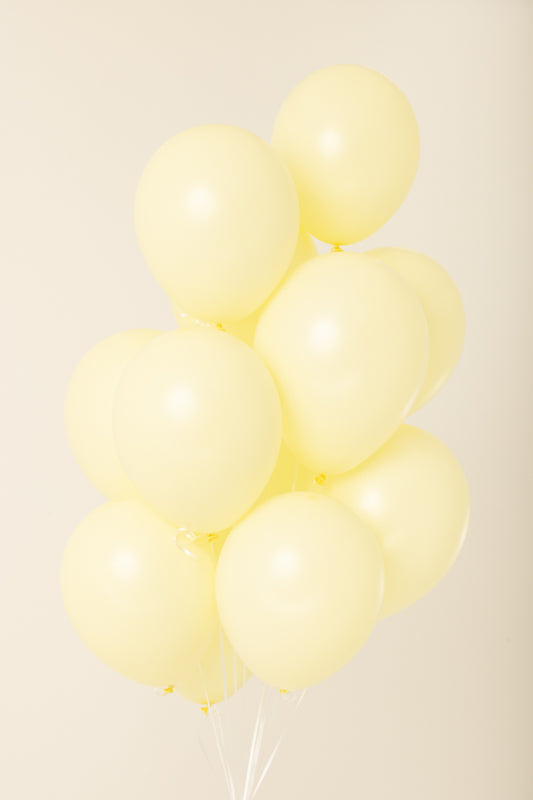 Cluster of pale yellow, round 11-inch latex balloons inflated with helium.