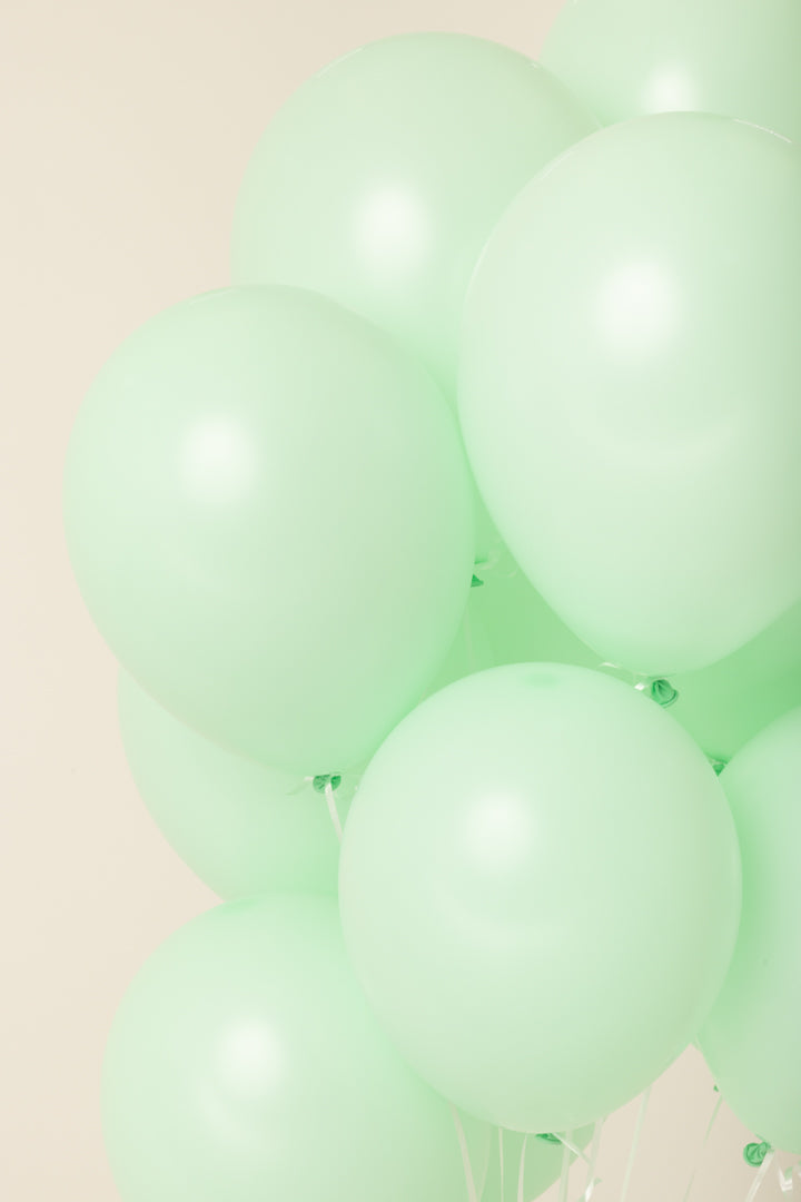 Cluster of pale green, 11-inch round latex balloons inflated with helium.