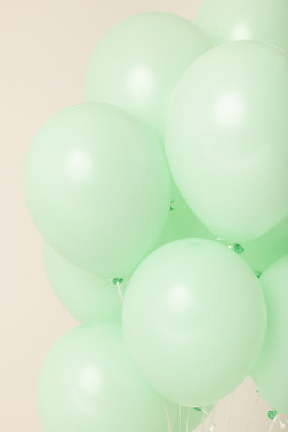 Cluster of pale green, 11-inch round latex balloons inflated with helium.