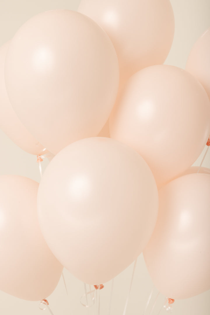 Glossy pale pink latex balloons inflated and tied, smooth surface, round shape, 11 inches.