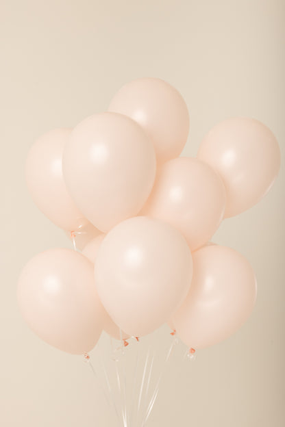 Cluster of pale pink 11-inch latex helium balloons with white strings visible.