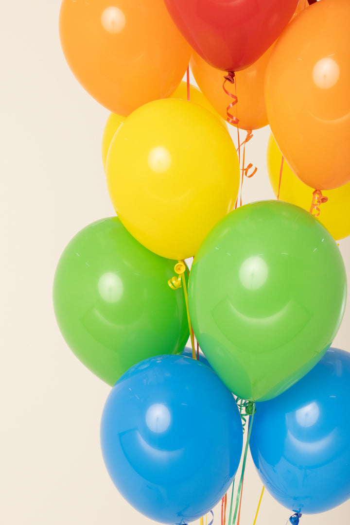 Glossy helium-inflated latex balloons in red, orange, yellow, green, and blue, shiny and round.