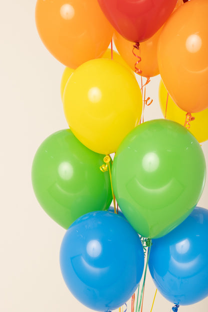 Glossy helium-inflated latex balloons in red, orange, yellow, green, and blue, shiny and round.