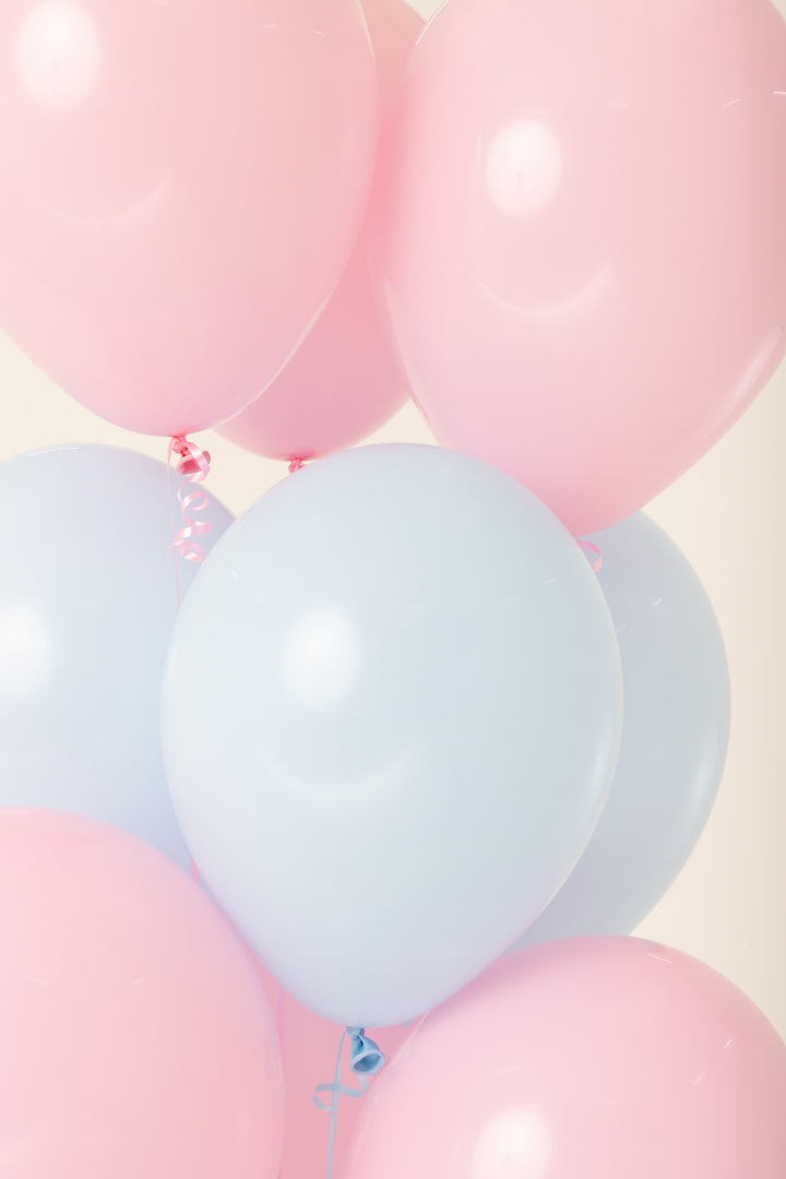 Helium-inflated latex balloons in pastel pink and light blue, glossy finish, 11-inch round shape.