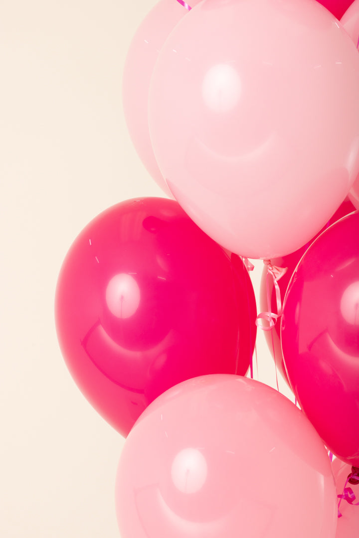 Cluster of pink and fuchsia 11-inch round latex balloons inflated with helium.
