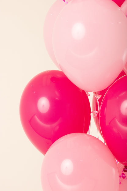 Cluster of pink and fuchsia 11-inch round latex balloons inflated with helium.