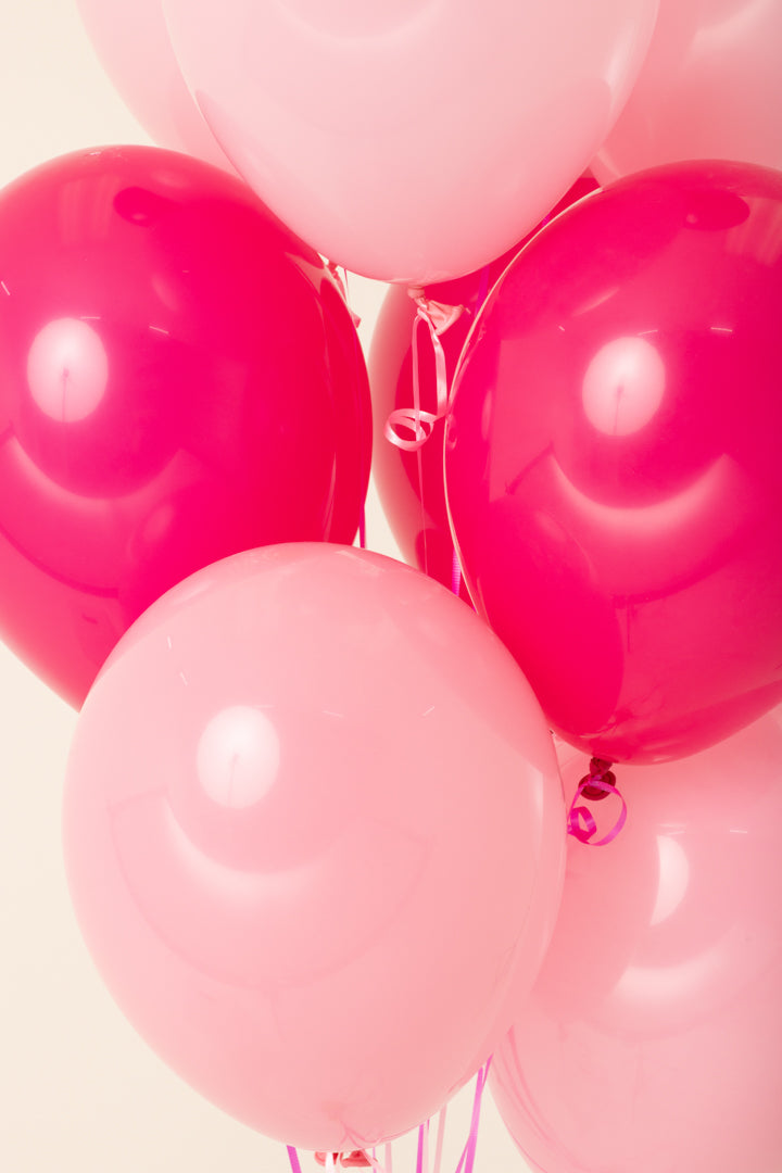 Cluster of shiny pink and light pink 11-inch latex balloons inflated with helium.