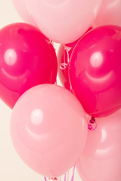 Cluster of shiny pink and light pink 11-inch latex balloons inflated with helium.