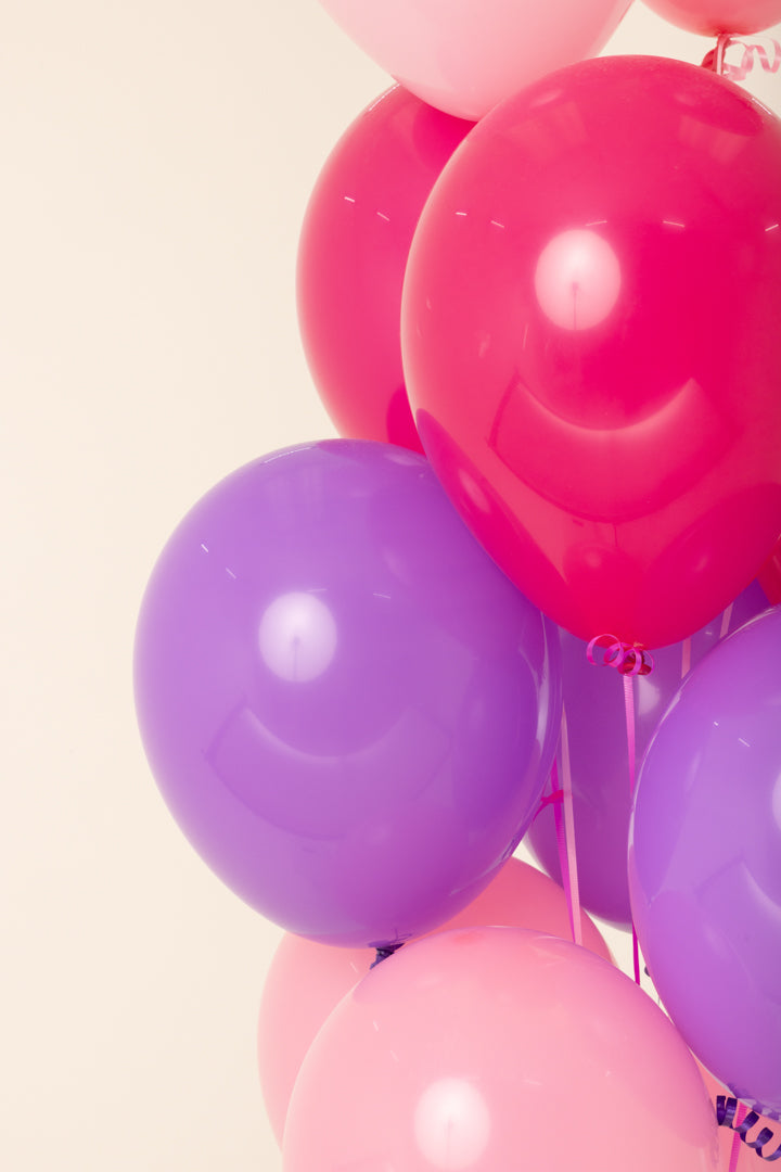 Cluster of helium-inflated 11-inch latex balloons in pink, red, and purple colors.