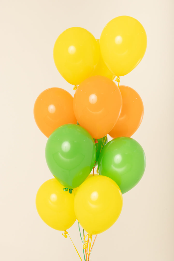 Cluster of 11-inch round latex balloons in yellow, orange, and green, helium-inflated and tied together.