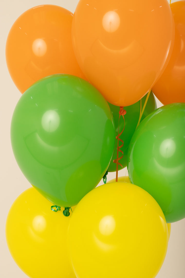 Bright orange, green, and yellow helium inflated 11-inch latex balloons with curled ribbons.
