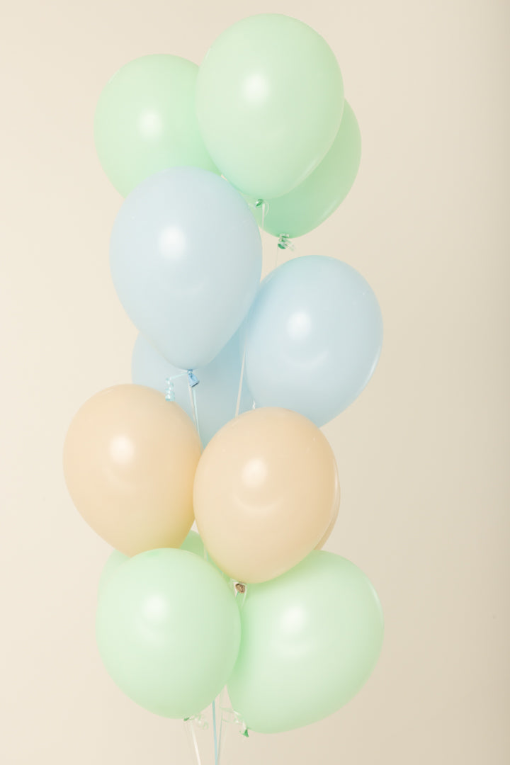 Cluster of pastel latex balloons in light green, blue, and peach, 11 inches, helium inflated.