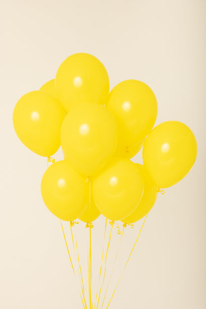 Cluster of nine bright yellow 11-inch round latex balloons inflated with helium and floating upright.