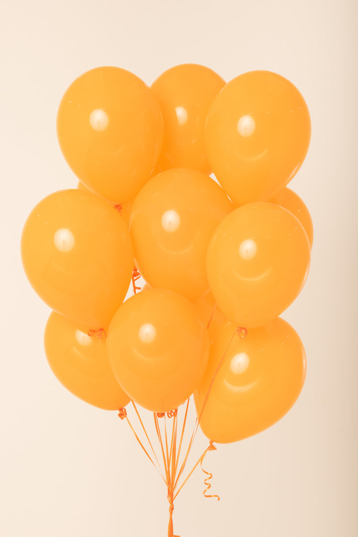 Cluster of eleven bright orange latex balloons inflated with helium, round shape, glossy finish.