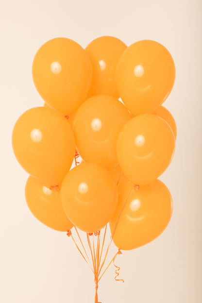 Cluster of eleven bright orange latex balloons inflated with helium, round shape, glossy finish.