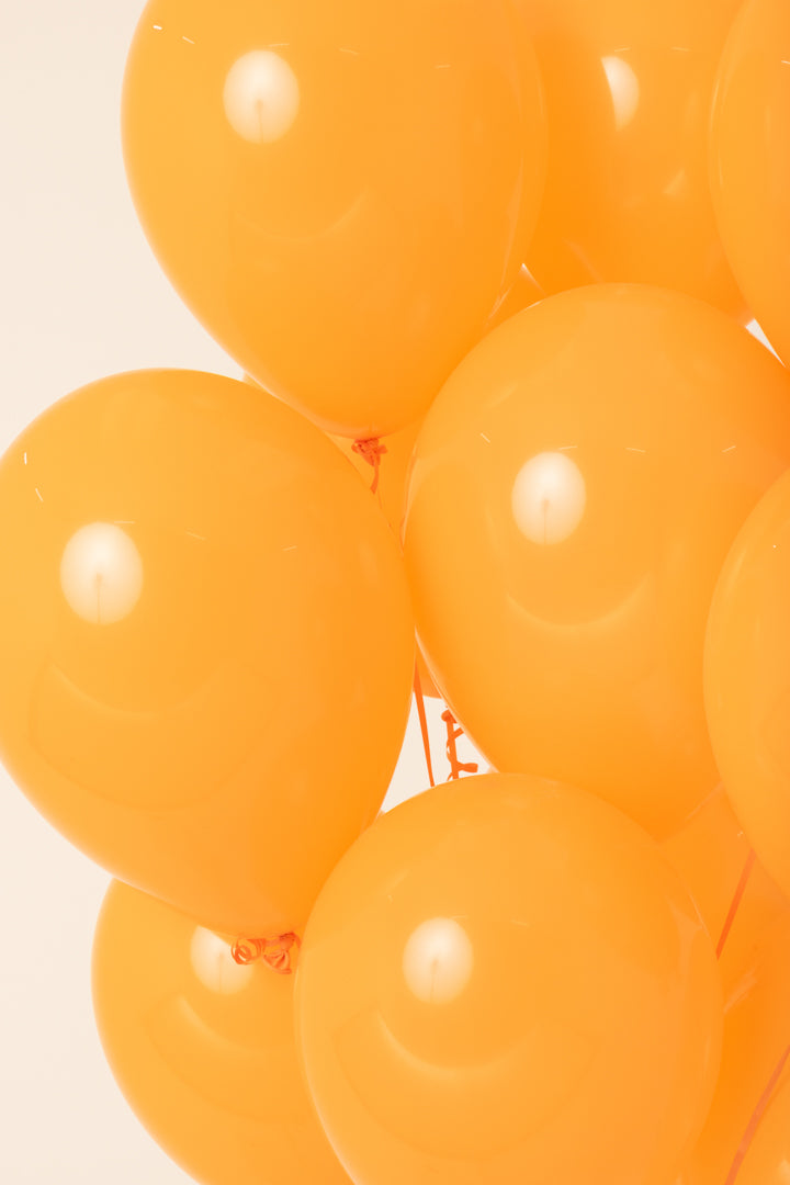 Bright orange glossy helium-filled latex balloons with a smooth, rounded 11-inch shape.