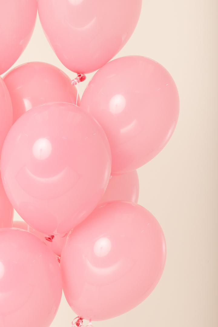 Cluster of shiny pink latex balloons inflated with helium, each about 11 inches in diameter.
