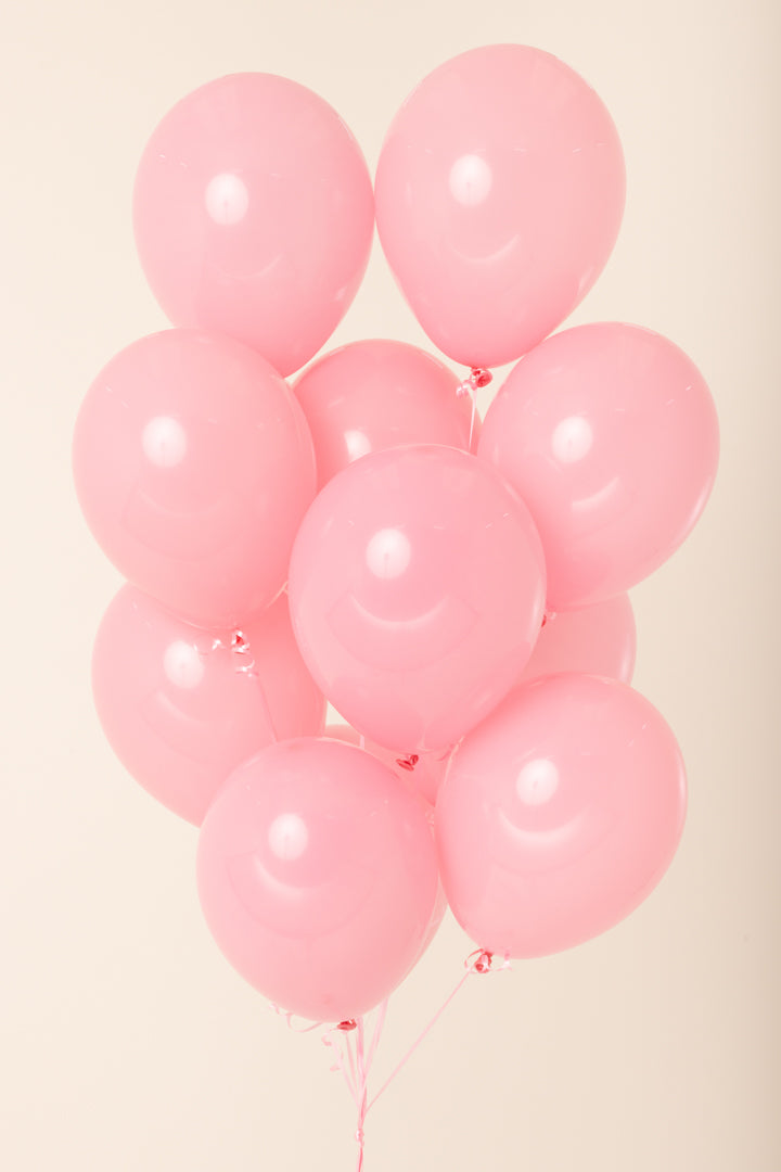Cluster of ten glossy light pink latex balloons inflated and grouped together against a neutral background.