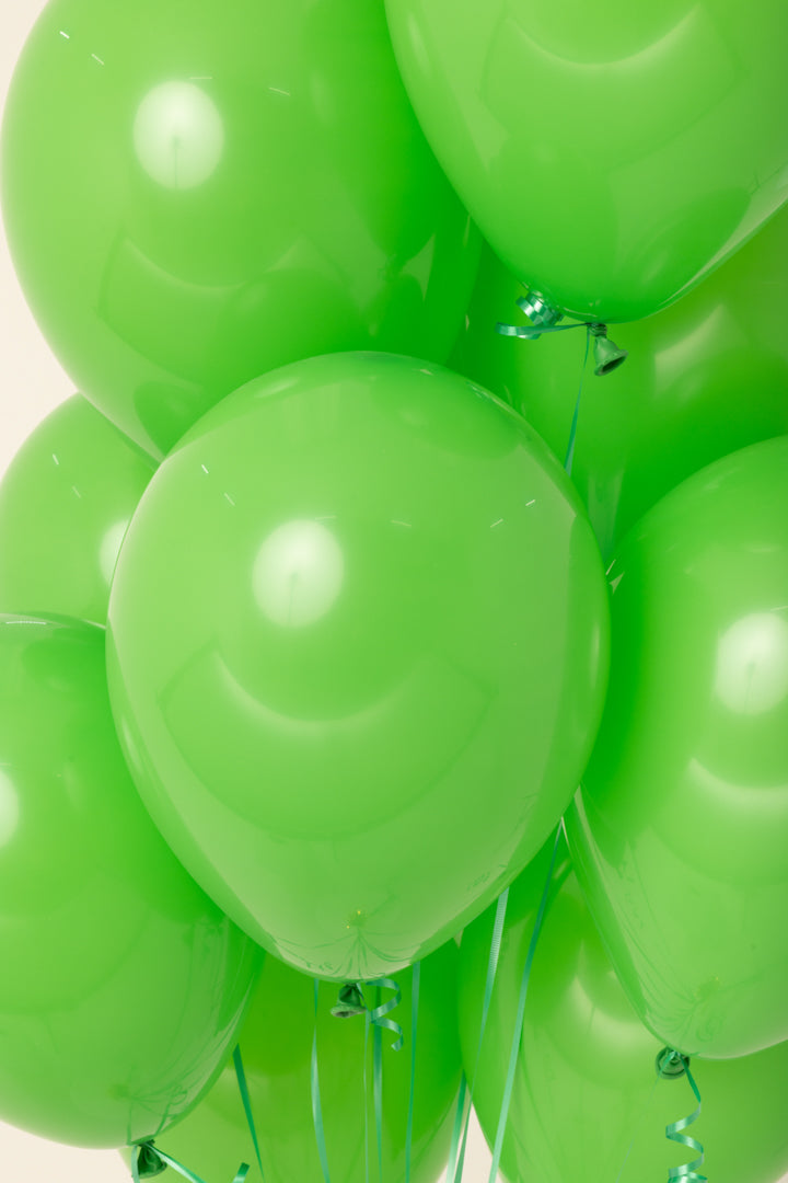 Bright green 11-inch round latex balloon inflated with helium.