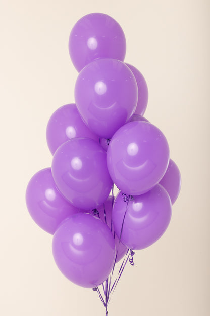 Cluster of eight glossy purple latex balloons inflated with helium against a light background.