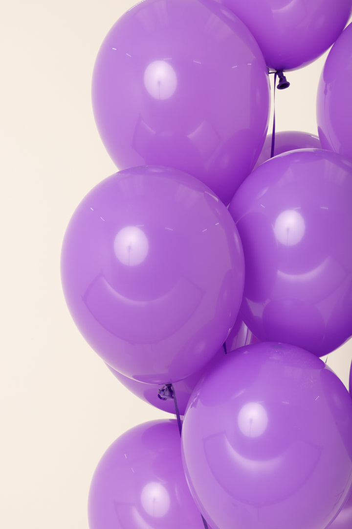 Glossy purple latex balloons inflated with helium, 11 inches round, single count.