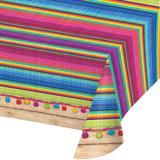 Rectangular plastic tablecover with vibrant serape stripes in pink, blue, green, and yellow, featuring colorful pom-poms.