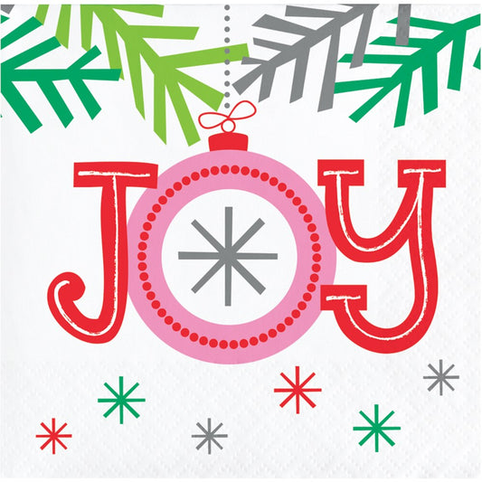 White beverage napkin with red "JOY" lettering, green and gray pine branch accents, and colorful snowflakes.