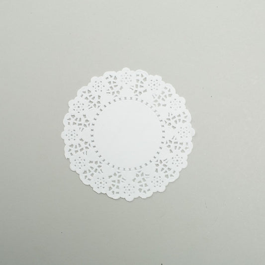 White round paper doily with intricate lace-like cutout patterns and scalloped edges, 4.5 inches in diameter.