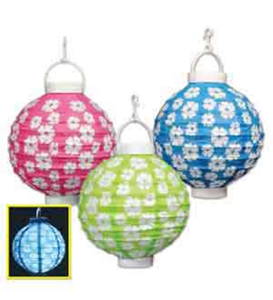 Set of three round paper lanterns in pink, blue, and green with white hibiscus flower patterns and metal hanging hooks.