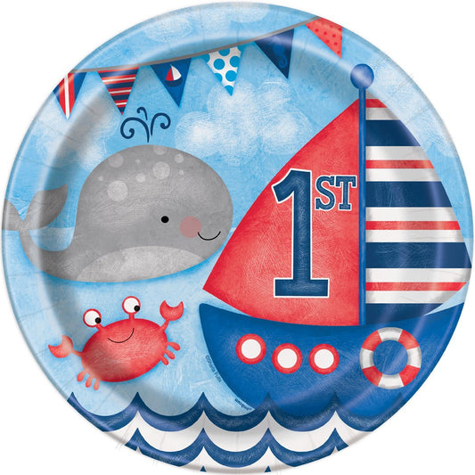 Round paper plate with a smiling gray whale, red crab, blue and red sailboat, and nautical flags on a light blue background.