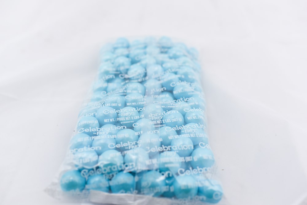 Clear plastic bag filled with shiny, round powder blue gumballs arranged in neat rows.