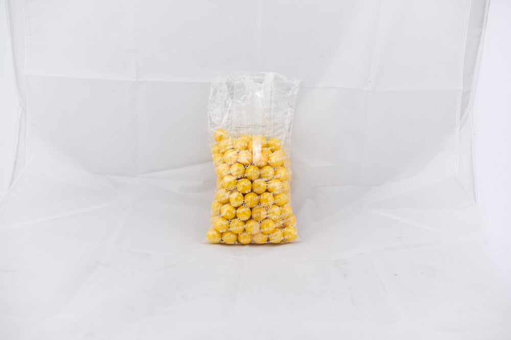 Clear plastic bag filled with shiny yellow gumballs against a white background.
